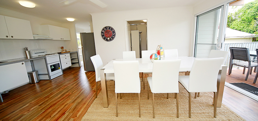 Dining room with white table and chairs on a natural rug and floorboards