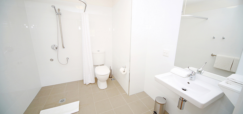Wet room style bathroom with tiles on floor and walls, toliet, shower and hand basin