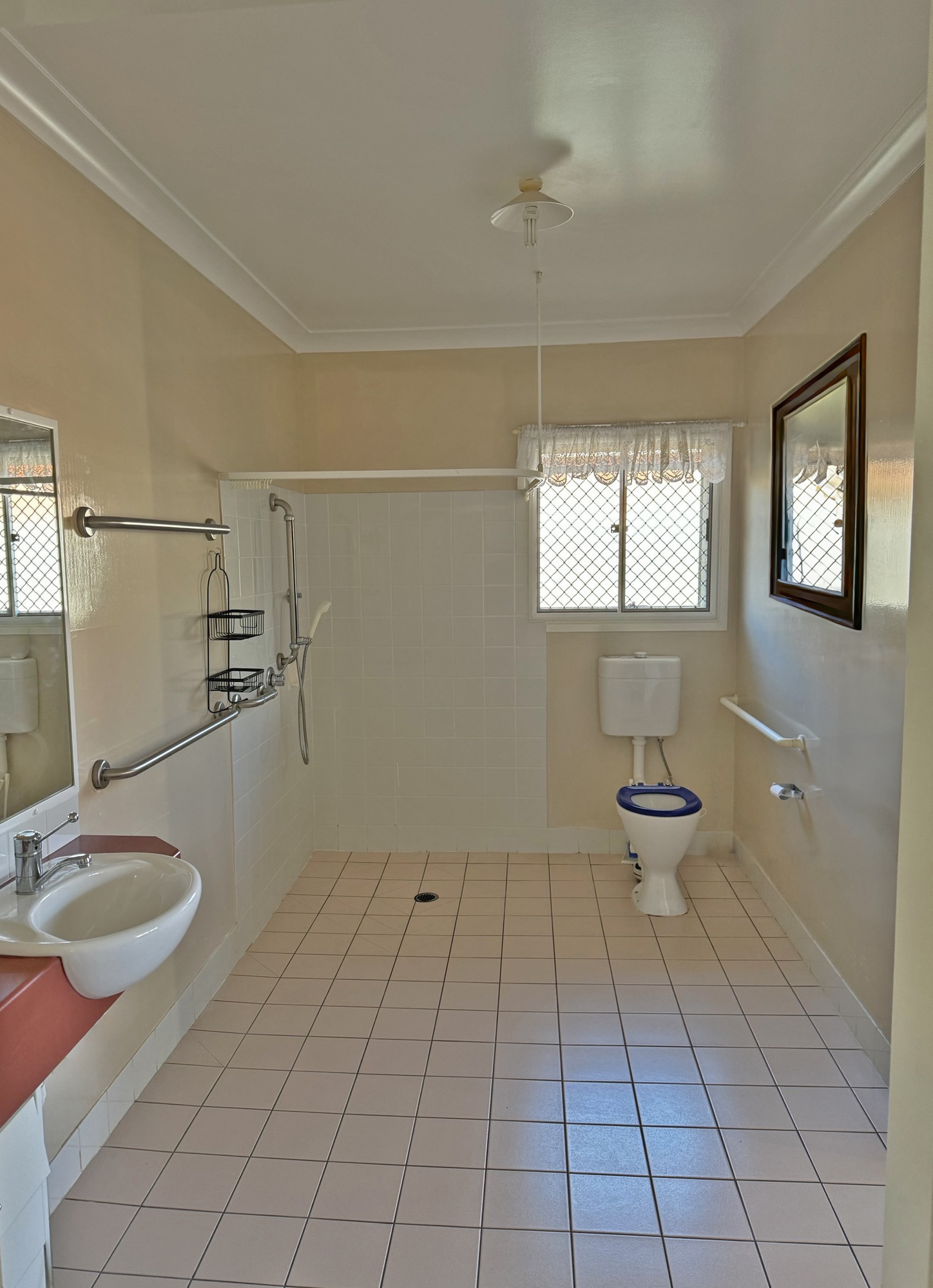 An image showing the bathroom, there is a shower, tiling and a mirror visible.