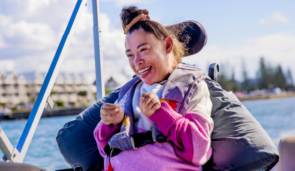 A woman in a wheelchair is on a boat sailing down a river