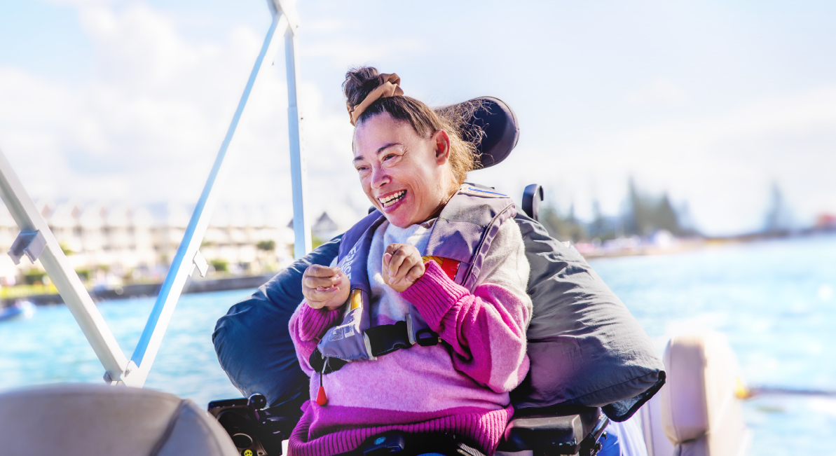 A woman in a wheelchair is on a boat sailing down a river