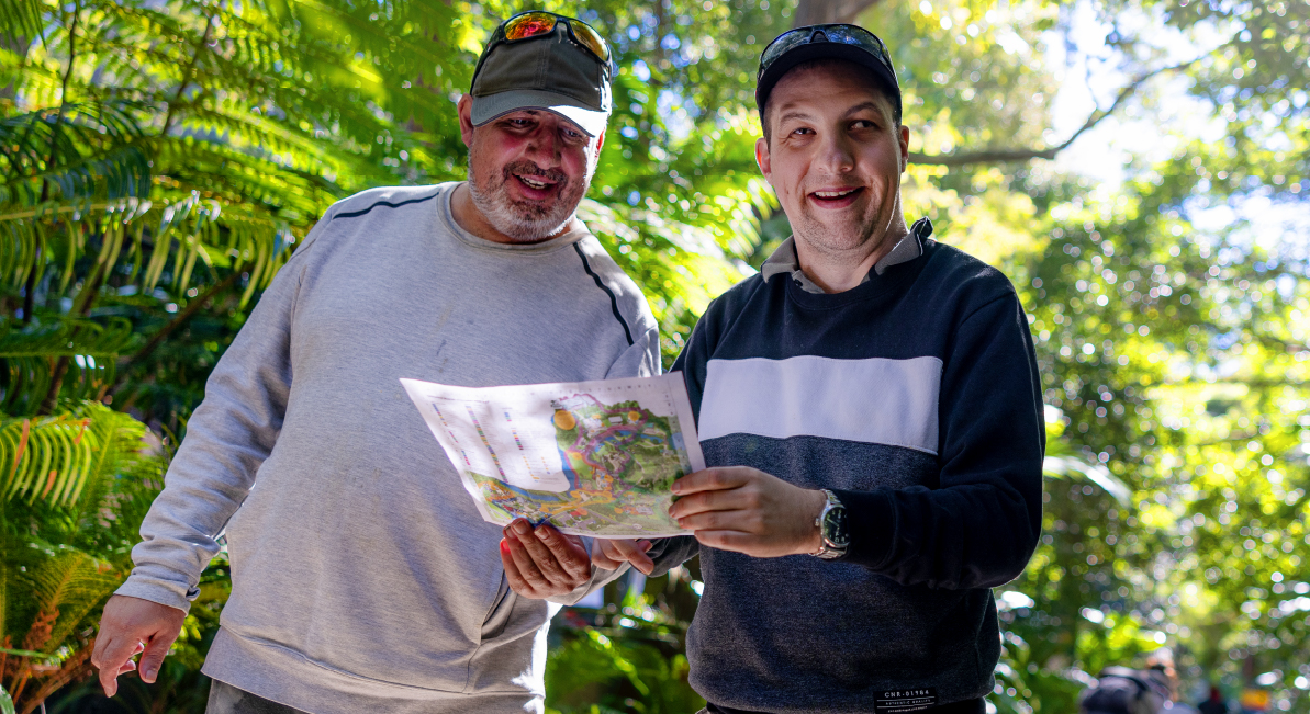 Two people are walking in a rainforest and holding a map