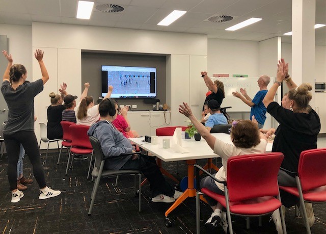 An image of people looking towards a screen watching basketball