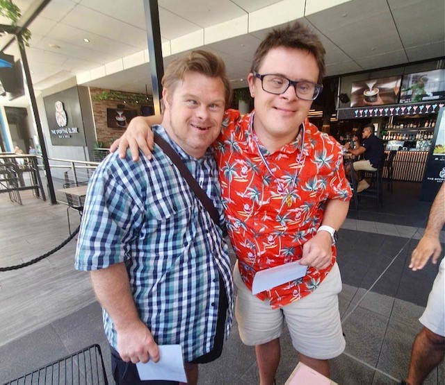 Two men embracing and smiling at the camera