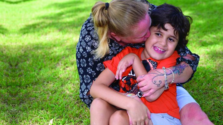 A mother and son in an embrace, sitting on grass